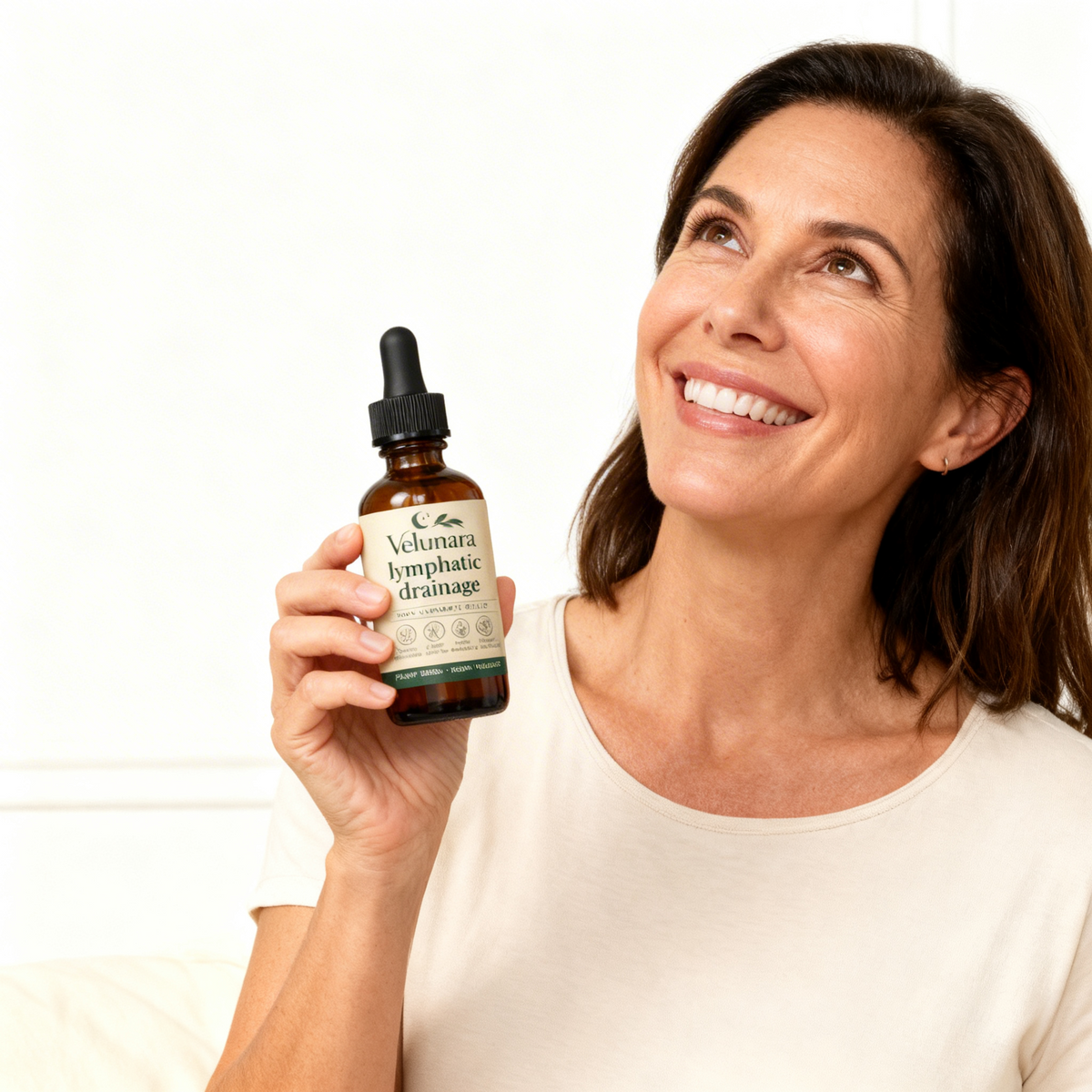 Woman holding a bottle of Velunara lymphatic drainage product against a white background
